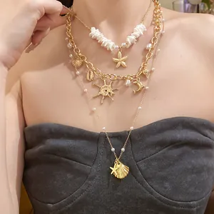 Vista dettagliata di una collana d'oro a strati con perle e vari ciondoli a tema marino