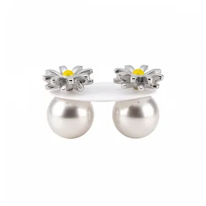 Eleganti orecchini a margherita in argento con grandi perle bianche su un supporto bianco