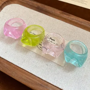 Close-up of colorful irregular resin rings in pink, green, and blue on a tray