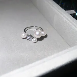 Macro detail of elegant silver-toned open ring with pearls and brilliant zircon stone