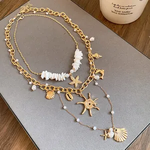 Dettaglio ravvicinato di collana dorata a strati con perle, conchiglie e ciondoli a stella
