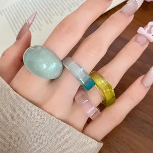 Detail of four colorful resin rings with smooth finishes and irregular shapes on hand