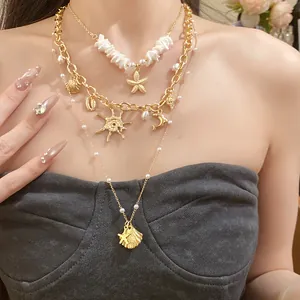 Dettaglio della collana a strati dorata con perle, conchiglie e ciondoli a stella marina