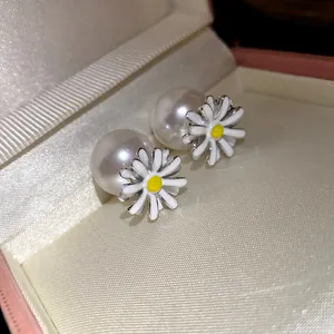 Primo piano dettagliato di orecchini a margherita con grandi perle bianche.