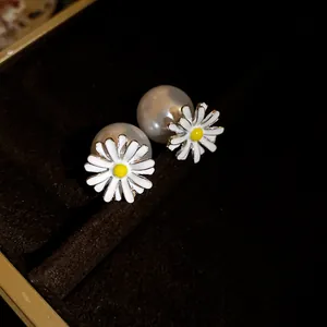 Primo piano di orecchini a margherita con grandi perle in un portagioie di velluto scuro