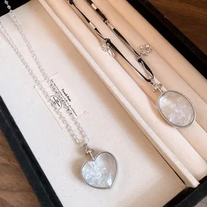 Primo piano di pendenti a cuore e ovali con intarsio di pietre su catene a perline