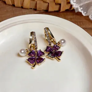 Elegant gold-plated hoop earrings featuring purple clover gemstones and pearl charms.