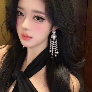 Close-up of elegant silver needle pearl tassel earrings worn by a model in vintage style.