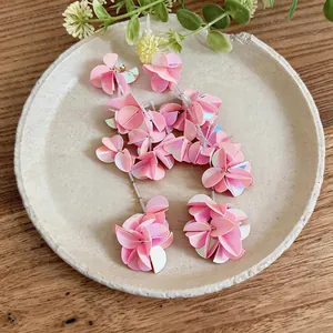 Dettaglio ravvicinato di orecchini a nappa con petali di conchiglia rosa cangiante