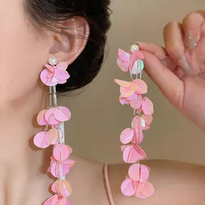Dettaglio di orecchini a nappa con petali rosa iridescenti e eleganti perni di perle
