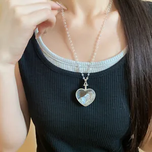 Vista dettagliata della collana con ciondolo a cuore e perle trasparenti su modella