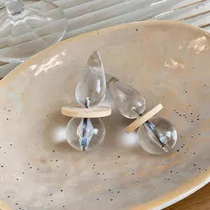 Primo piano di orecchini a goccia in resina con disco di legno e ago d'argento.