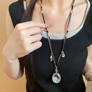 Dettaglio della collana con ciondolo in cristallo e croce indossata da una modella