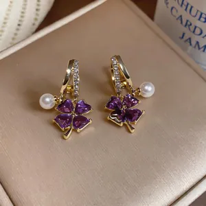 Detailed macro view of French style purple heart clover earrings with white pearls.