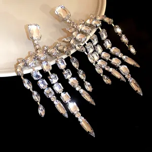 Dettaglio macro di eleganti orecchini a nappa in argento con cristalli quadrati lucidi.