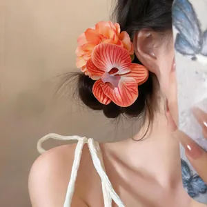 Dettaglio di una clip per capelli a forma di orchidea in tessuto arancione su una donna.