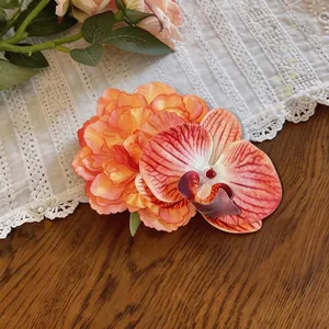Dettaglio di un'elegante clip per capelli in tessuto arancione con fiori di orchidea