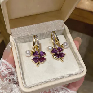 Close-up of French style earrings with purple flower stones and white pearls in a box