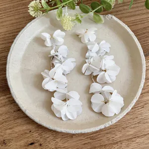 Vista dettagliata di eleganti orecchini a nappa con petali bianchi e accenti oro.