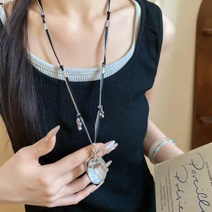 Dettaglio di una collana d'argento con ciondolo in cristallo indossata da una modella