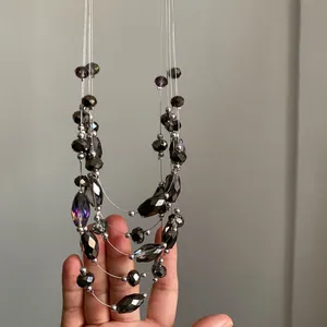 Primer plano de collar bohemio de varias capas con cuentas talladas oscuras y plata