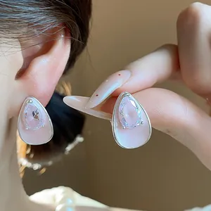 Detailed close-up of teardrop zircon earrings featuring pink resin base and silver needles.