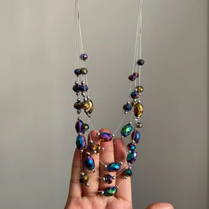 Mano sosteniendo un collar bohemio de varias capas con cuentas facetadas.