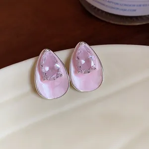Close-up detail of pink zircon and enamel teardrop stud earrings with a silver finish