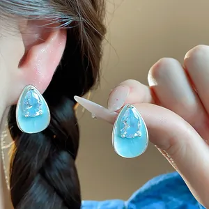 Detail of teardrop earrings featuring light blue enamel and sparkling zircon accents.