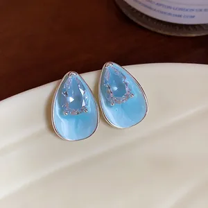 Macro detail of light blue enamel water drop earrings with sparkling teardrop zircon