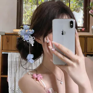Dettaglio di un'elegante molletta per capelli a fiori blu con petali pendenti su uno chignon.