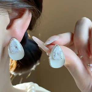 Detail of teardrop earrings with sparkling zircon and white enamel finish