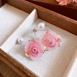 Elegante rosa Rosen- und Perlenohrstecker in einer Vintage-Schmuckschatulle aus Holz