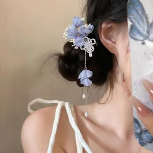 Primo piano di elegante fermaglio per capelli con fiori di stoffa viola e nappa lunga.
