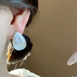 Close-up view of a silver waterdrop earring with zircon and white enamel detail