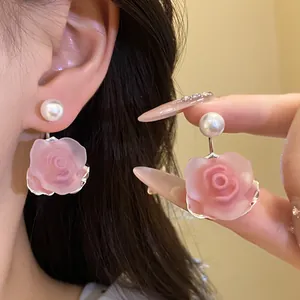 Detail der süßen rosa Rosen- und Perlenohrringe mit zarter Blütenblattstruktur