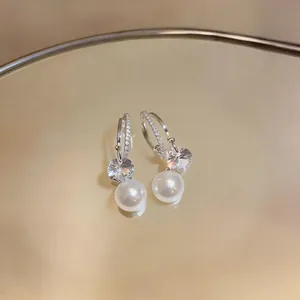 Detail shot of elegant silver C-shaped earrings with zircon and white pearls