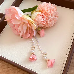 Dettaglio di un fermaglio per capelli a fiori rosa con eleganti nappe di perle e boccioli