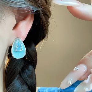 Close-up of light blue enamel waterdrop earring with sparkling zircon inlay