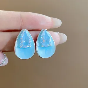 Close-up of teardrop stud earrings with light blue enamel and sparkling zircon