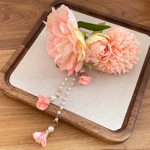 Dettaglio di un fermaglio per capelli a fiore in tessuto rosa con lunghe nappe di perle