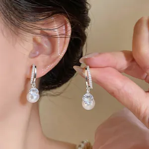 Detailed view of elegant silver hoop earrings featuring zircon and dangling pearls