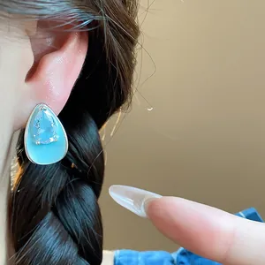 Detailed shot of a teardrop shaped earring featuring blue enamel and sparkling zircon