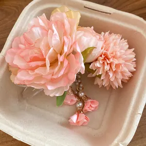 Dettaglio di una molletta per capelli con fiori rosa e nappine di perle eleganti.