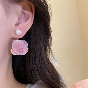 Detailaufnahme von süßen rosa gefrosteten Rosen- und Perlenohrringen am Ohr getragen
