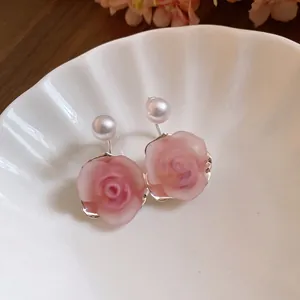 Detailansicht der rosa Harz-Rosenohrringe mit Perlenakzenten auf einer Keramikschale