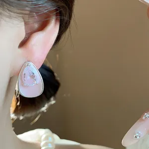 Detail of pink enamel teardrop earring with central clear zircon on silver post.