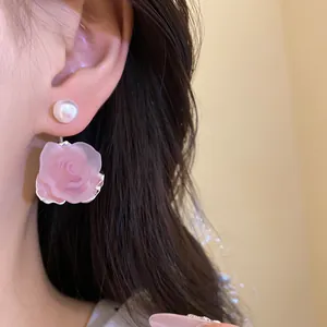 Nahaufnahme eines süßen rosa Rosenohrrings mit Perlenstecker am Ohr eines Modells für den Sommer