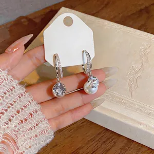 Detail view of silver C-shape earrings with sparkling cubic zirconia and white pearls