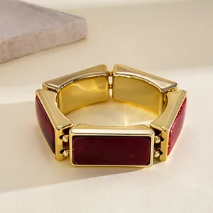 Macro detail of a vintage gold-plated bracelet featuring rectangular burgundy resin tiles